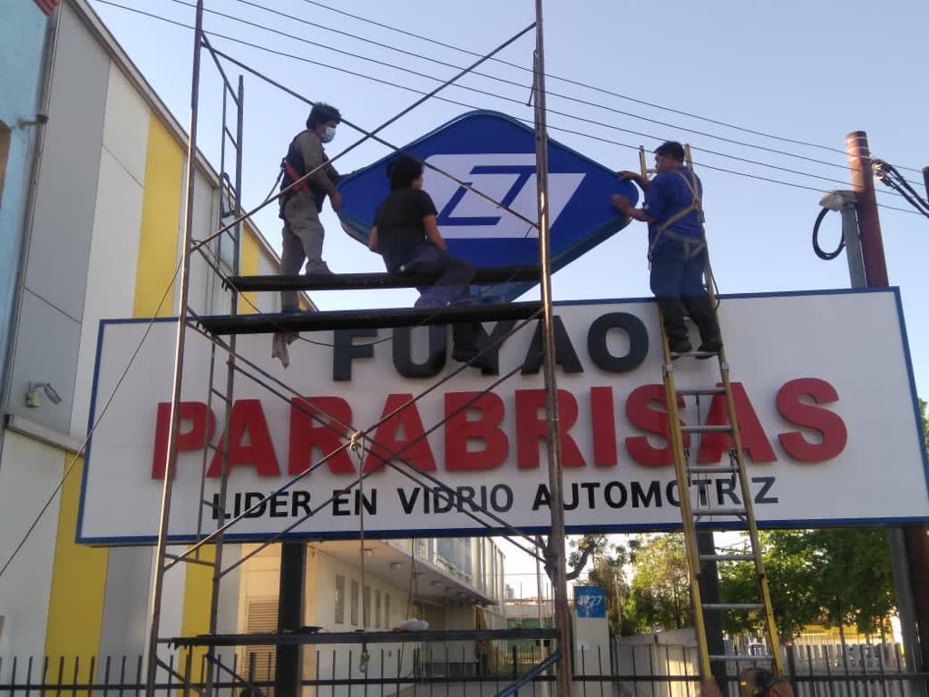 Equipo de técnicos instalando letras volumétricas corpóreas en altura con andamios